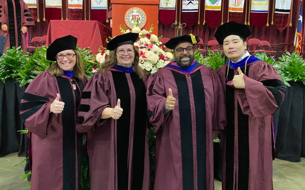 Doctoral Students posing with Gig 'Em thumbs