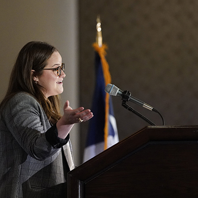 Woman speaking into a microphone at a lectern